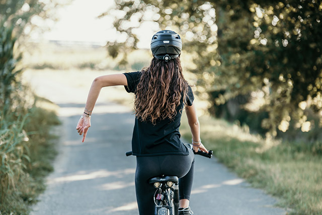 donna in bicicletta che segnala un ostacolo o una buca