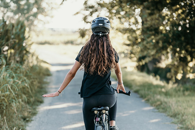 donna in bicicletta che segnala vetri o pavimento bagnato