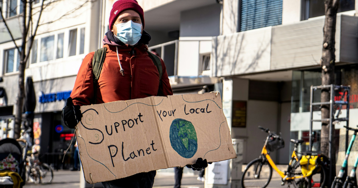 Manifestante con cartello 'support your local planet' per sottolineare l'importanza di proteggere il pianeta